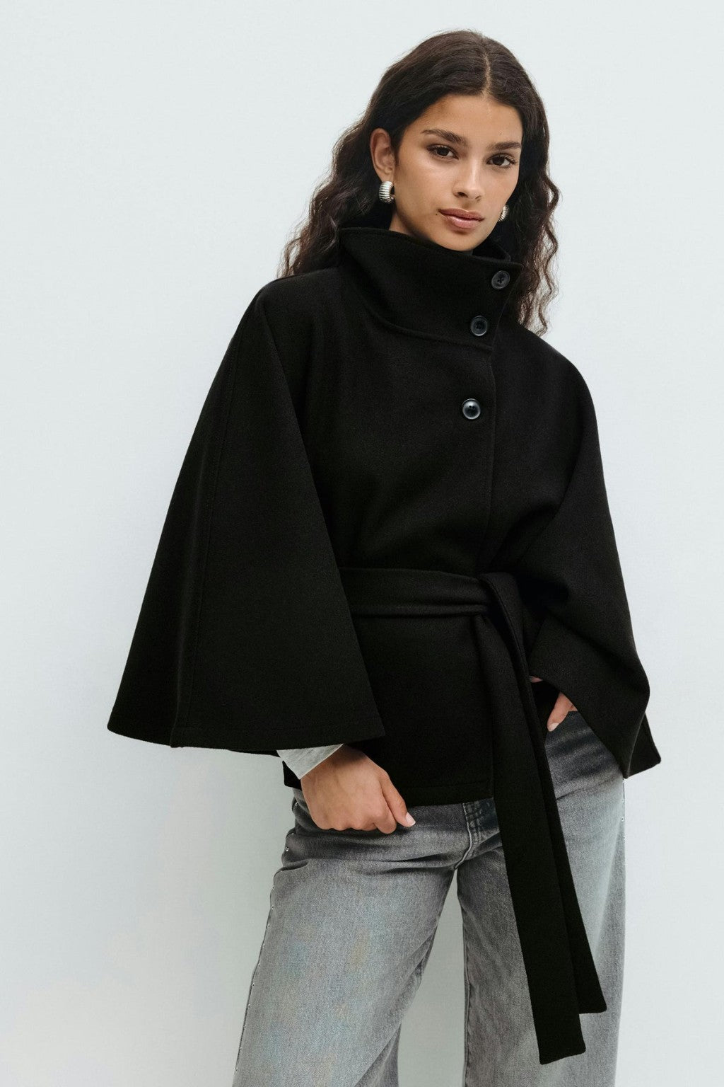 Model wearing the JANT belted poncho cape in black