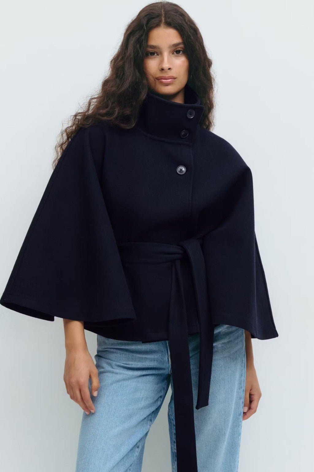 Model wearing the JANT belted poncho cape in navy